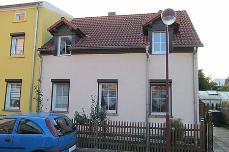 Reihenhaus mit zwei Stockwerken und leicht verschmutzter, rosaner Fassade