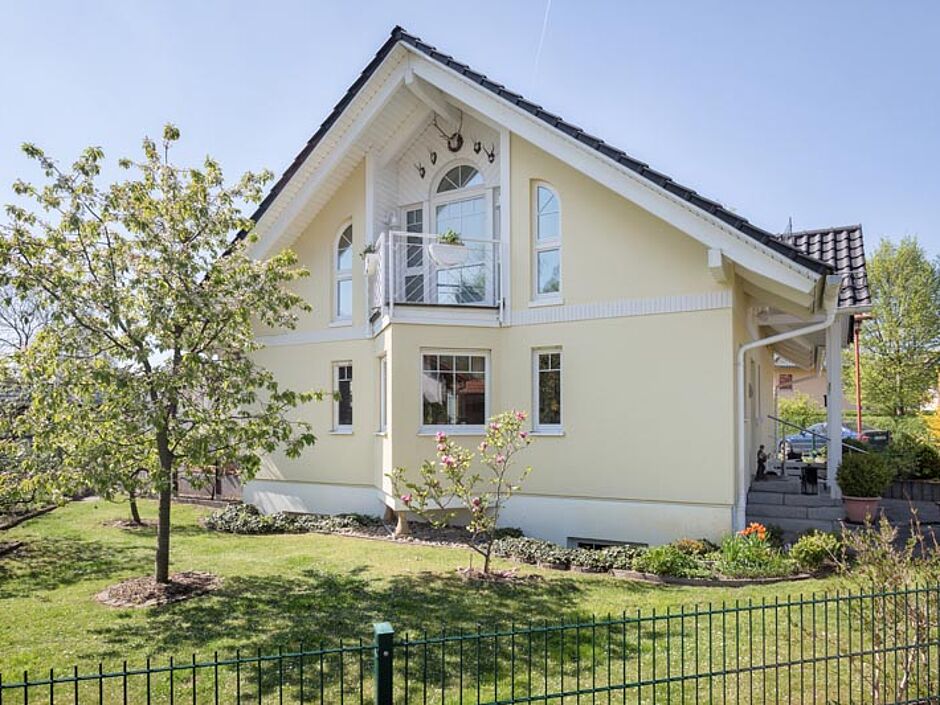 Pastellgelbes Haus umgeben von einem großen Garten
