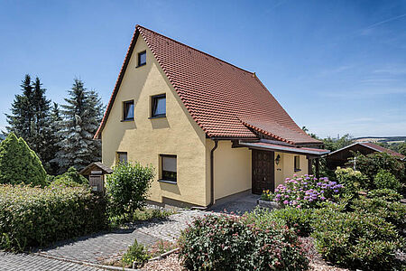 Gelbes Einfamilienhaus mit Satteldach und ebenmäßiger Fassade