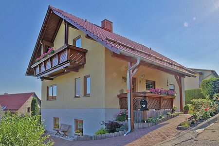 Dreistöckiges Haus mit gelber Fassade und weißem Fundament