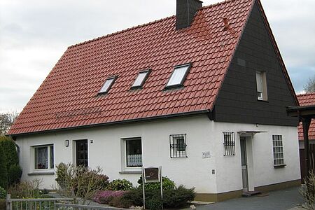 Einfamilienhaus mit weißer Fassade im Erdgeschoss und schwarzer Vertäfelung im Obergeschoss