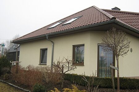 Cremefarbenes Bungalow mit Walmdach und veralteter Fassade