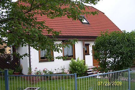 Ehemals weißes Haus mit Walmdach und ergrauter Fassade