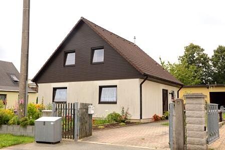 Haus mit weißer Fassade im Erdgeschoss und Holzverkleidung für erste Etage