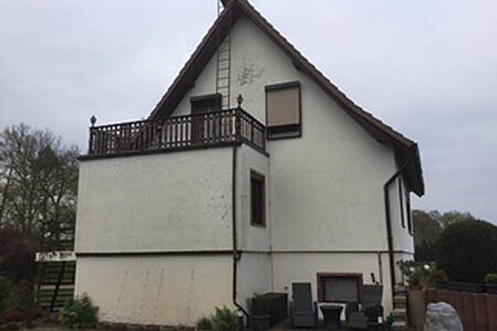 Dreistöckiges Einfamilienhaus mit stark verschmutzter, weißer Fassade