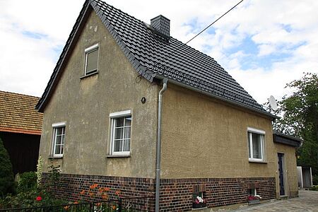 Braun verputztes Einfamilienhaus mit sanierungsbedürftiger Fassade