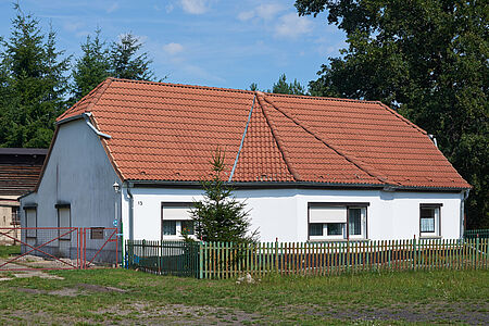 Zweistöckiges Wohnhaus mit Krüppelwalmdach und hellblauer Fassade